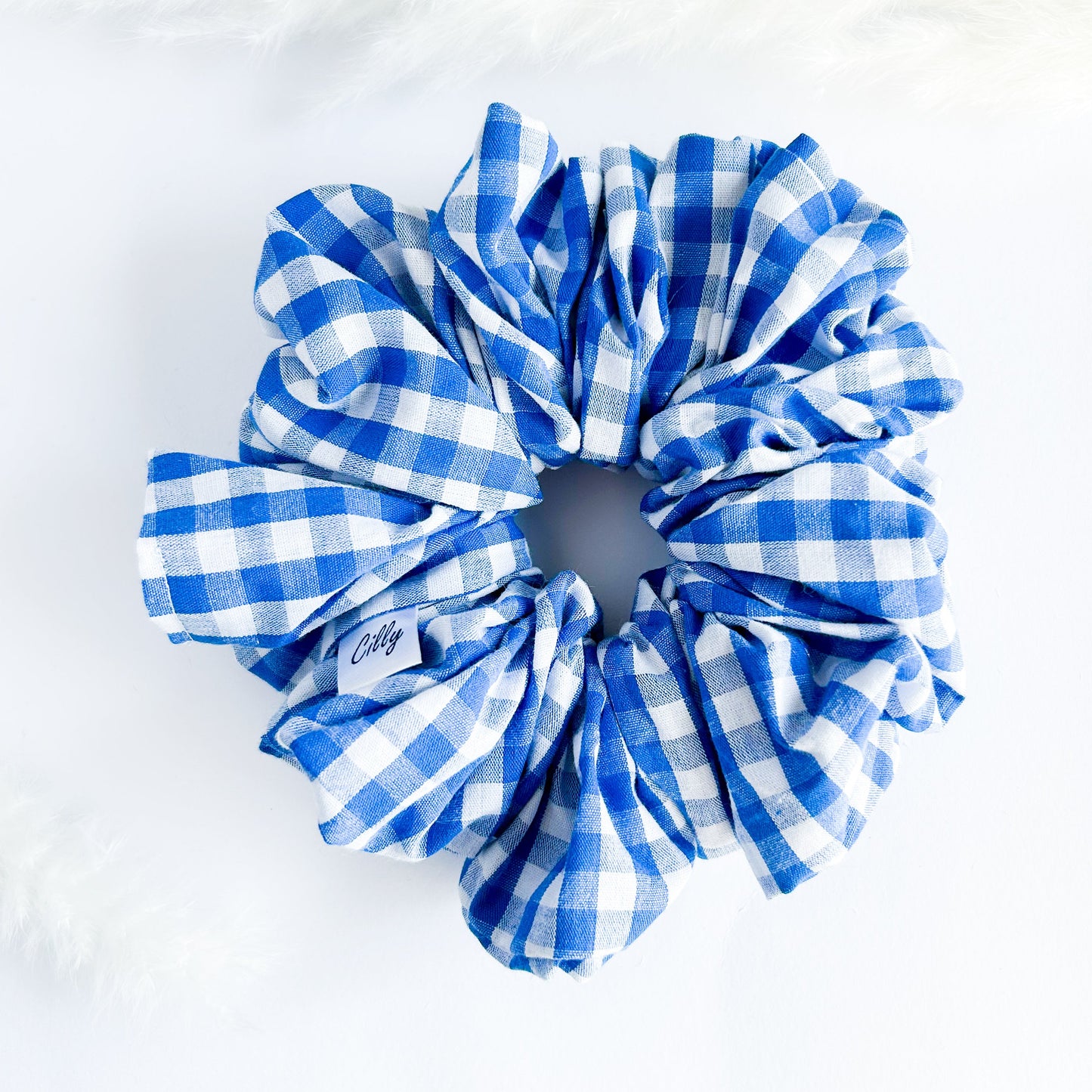Een blauw witte scrunchie met een gingham boerenruit blokjes patroon